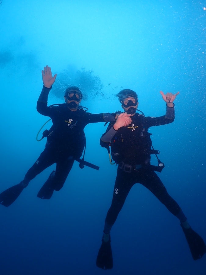 ハワイ・ワイキキの青い海で、手をつないで体験ダイビングを楽しむお父様と息子さん
