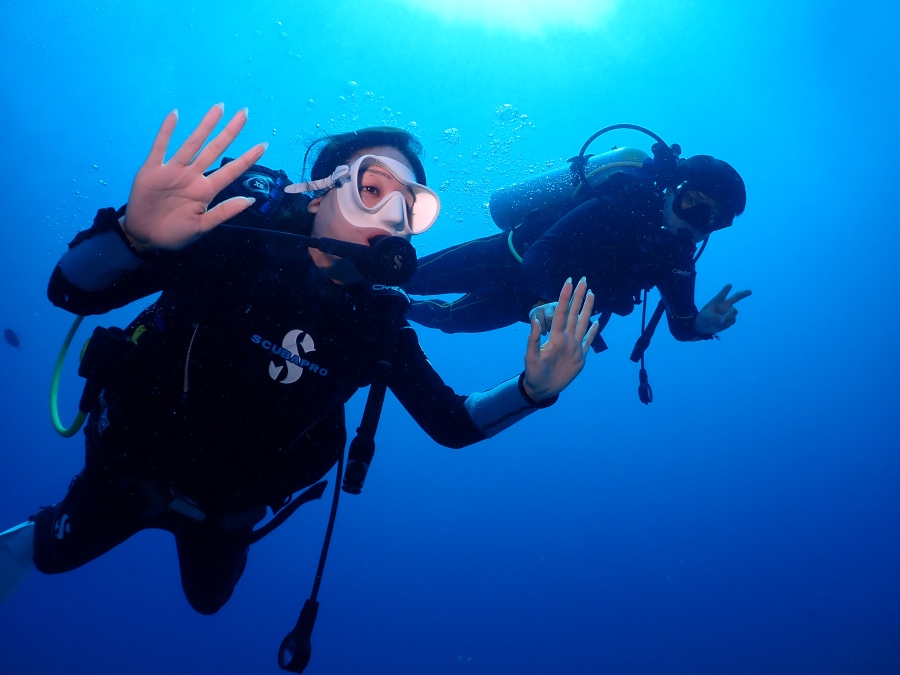 ハワイの海で体験ダイビングを楽しみ、カメラに手を振るお二人