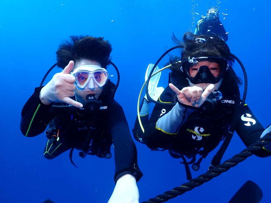ハワイの海でFUNダイビングを満喫し、シャカサインをするリピーターのお客様