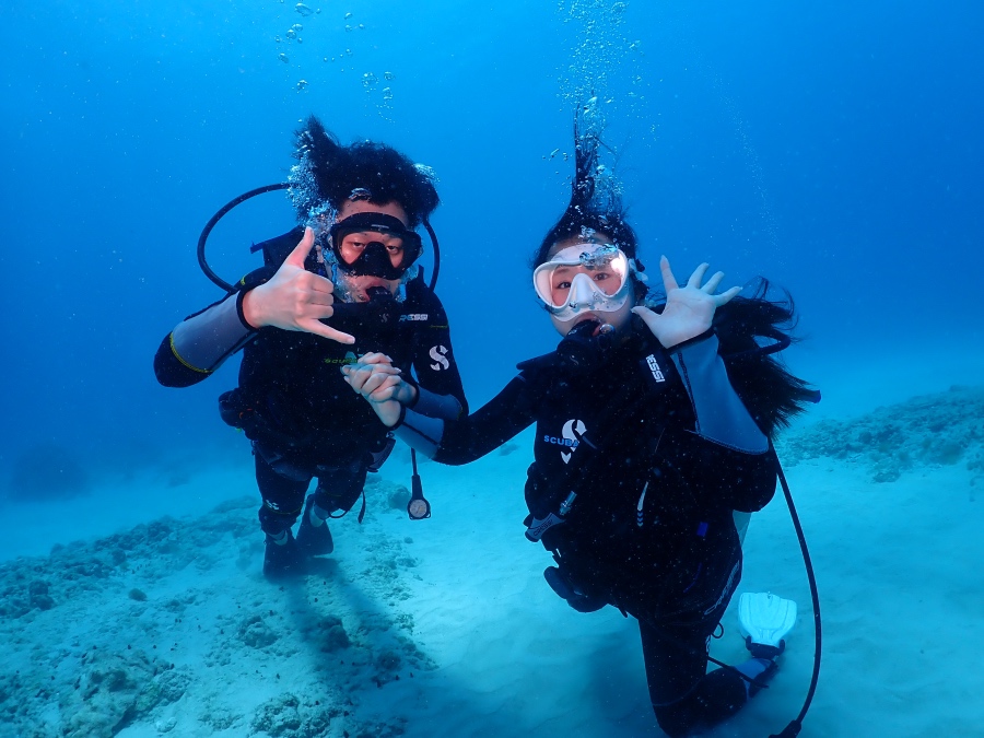 ハワイの綺麗な海でポーズをとるダイバーのお二人