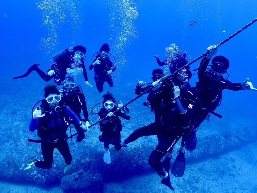 ハワイの海で潜降ロープに集まり記念撮影をする大人数グループのダイバー