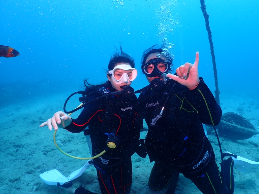 ハワイの海で潜降ロープにつかまりアロハポーズをする体験ダイビングの二人