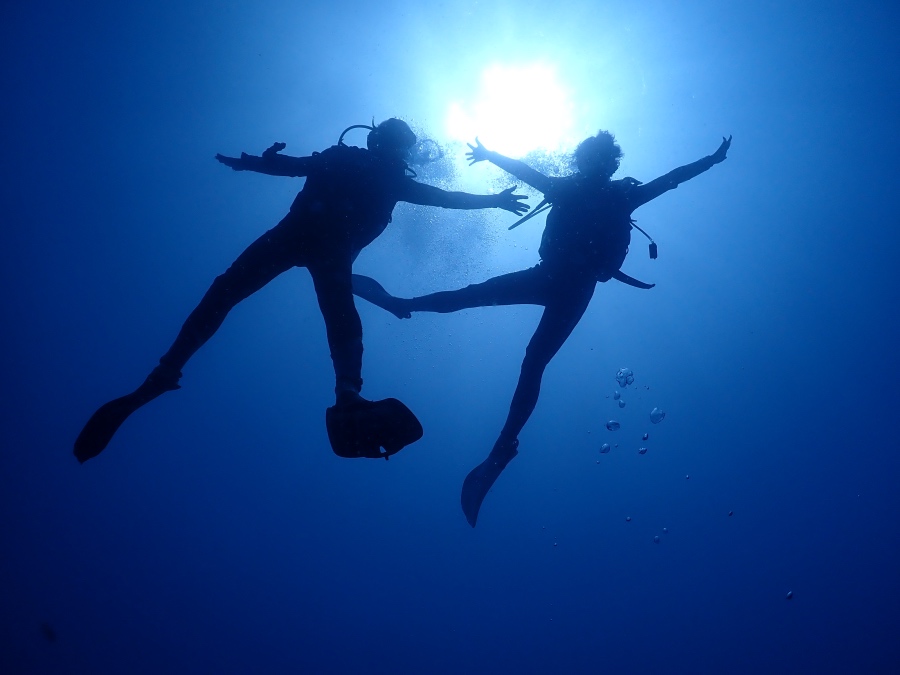 ハワイの強烈な太陽光に向かって手を広げて浮遊するダイバーの美しいシルエット