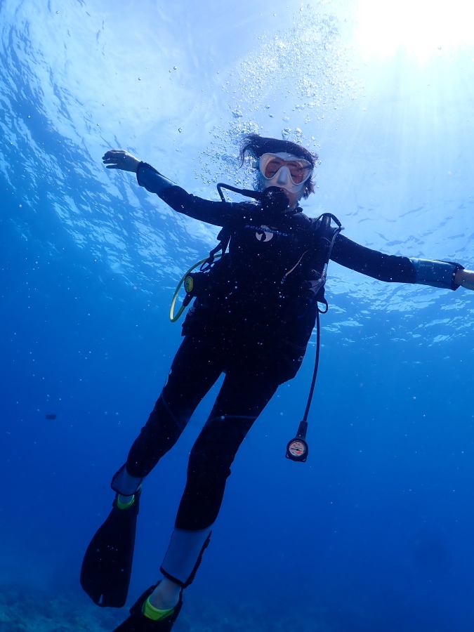 ハワイのクリアな海で水中に浮かびながら太陽の光を浴びるシニアの女性ダイバー