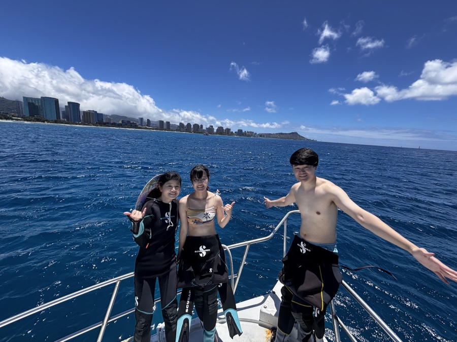 ハワイの青い海とダイヤモンドヘッドを背景にボート上で微笑むご家族