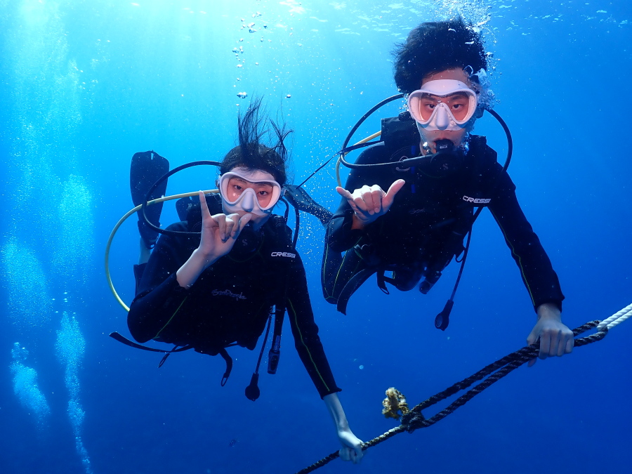 ハワイの海で潜降ロープをしっかり持ちアロハポーズをするファンダイバー