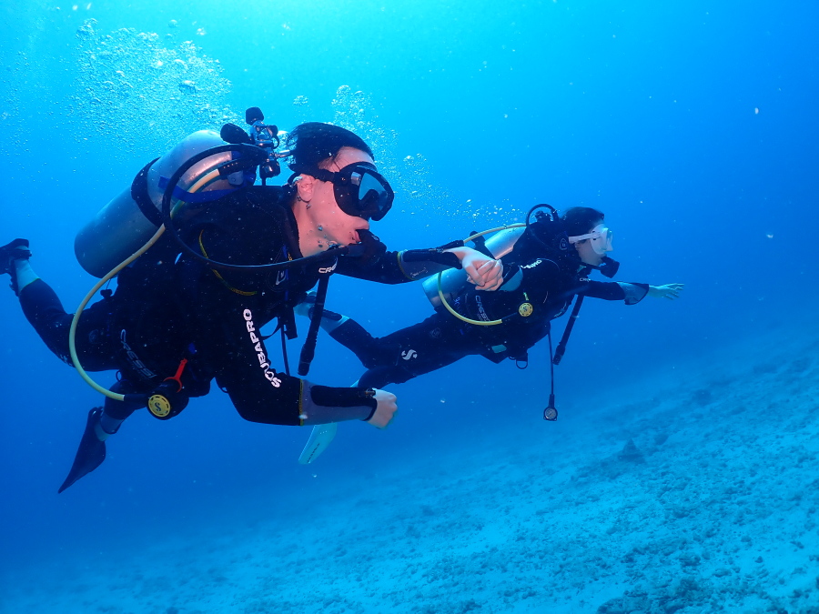 ハワイの透明度抜群の青い海で手をつないで仲良く泳ぐハネムーンの体験ダイバー