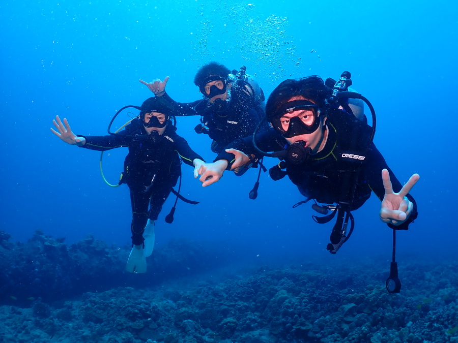 ハワイのクリアな海でご家族3名手をつないで笑顔でポーズをとる体験ダイバー