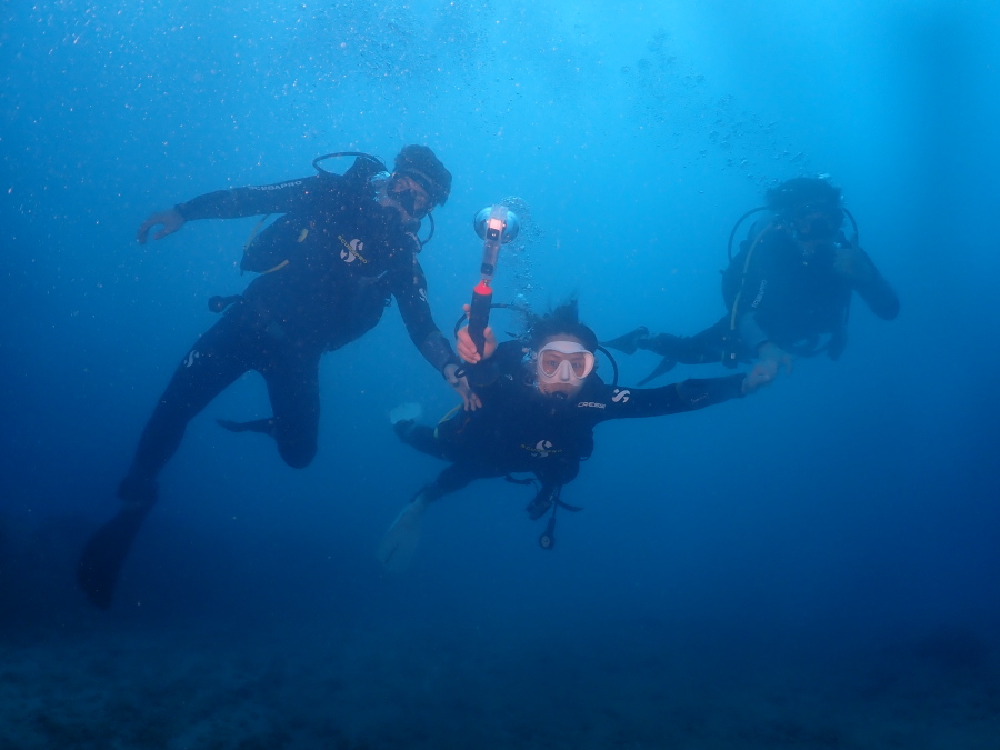 ハワイの青い海でご家族3人しっかり手をつなぎカメラを向けて泳ぐ体験ダイバー