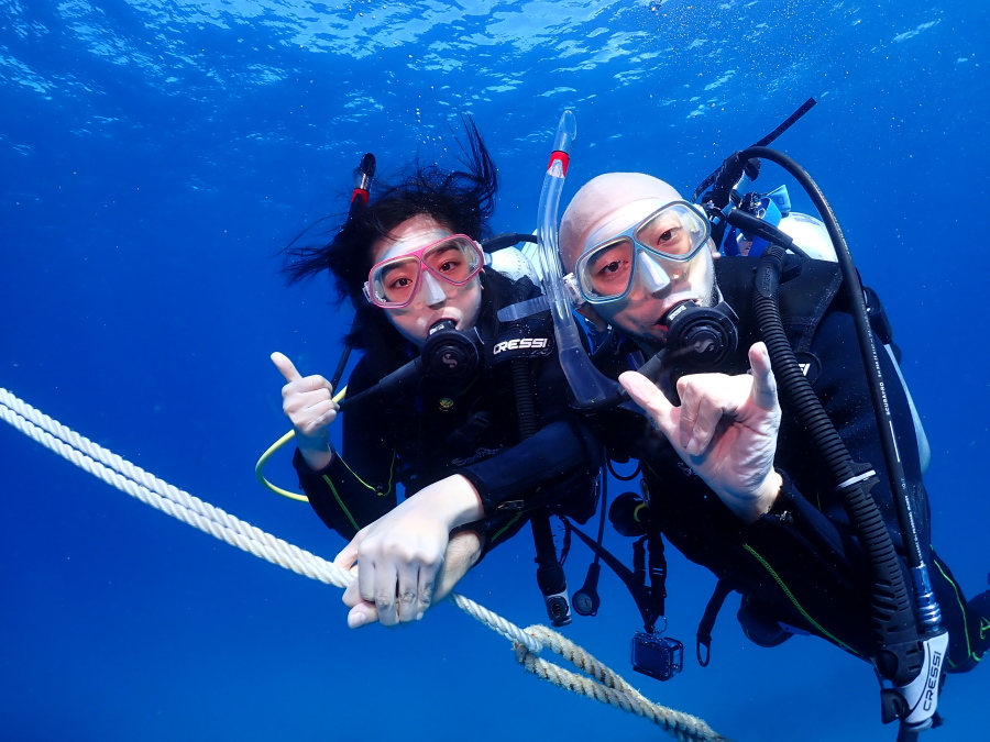 ハワイの海でロープにつかまりながら笑顔でシャカサインを決めるファンダイバー
